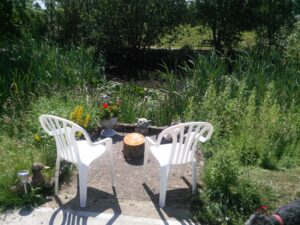 Chairs and table facing the garden and pond